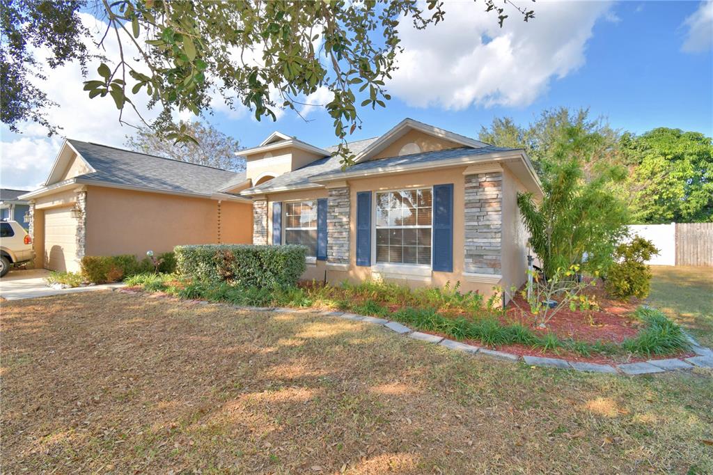 A single-story suburban house with a large front tree, green lawn, and concrete driveway — 3425 STONEWAY DRIVE, LAKELAND, FL