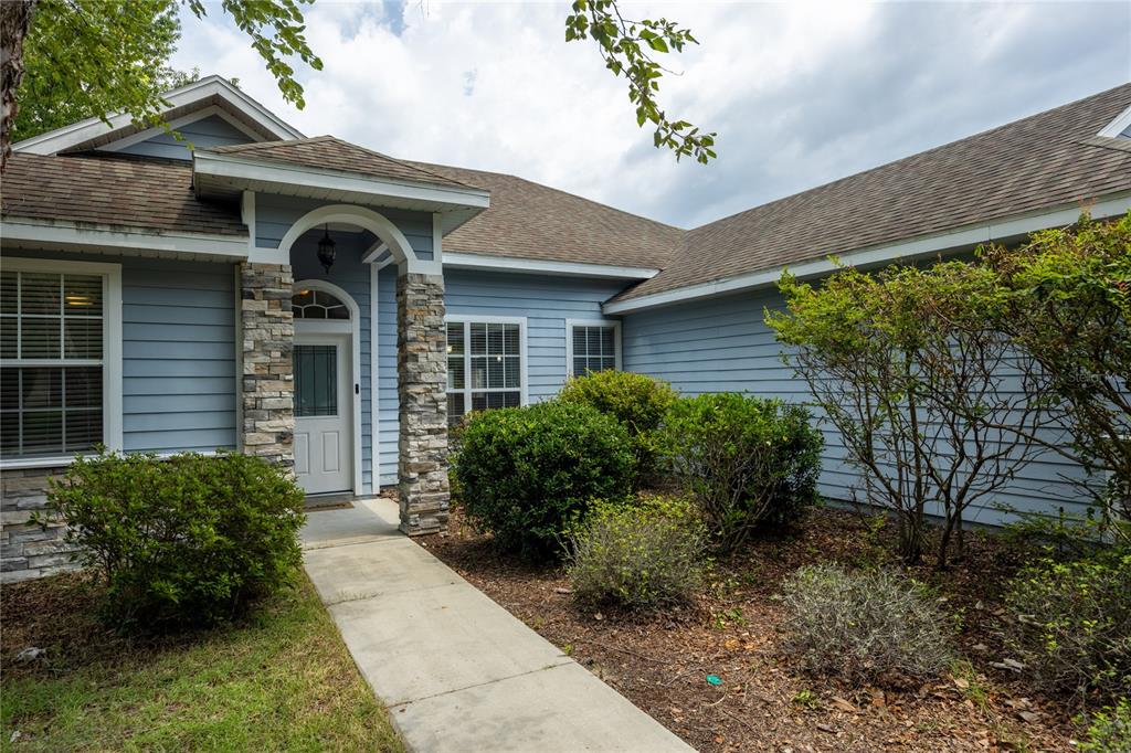 A blue-sided house with a stone-accented entryway and a concrete walkway leading to the door — 9004 SW 79TH AVENUE, GAINESVILLE, FL