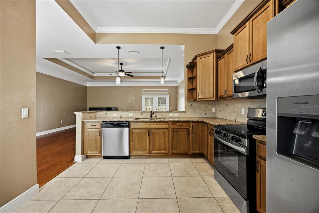 A kitchen with wood cabinets, stainless steel appliances, granite countertops, and tile flooring — 9004 SW 79TH AVENUE, GAINESVILLE, FL