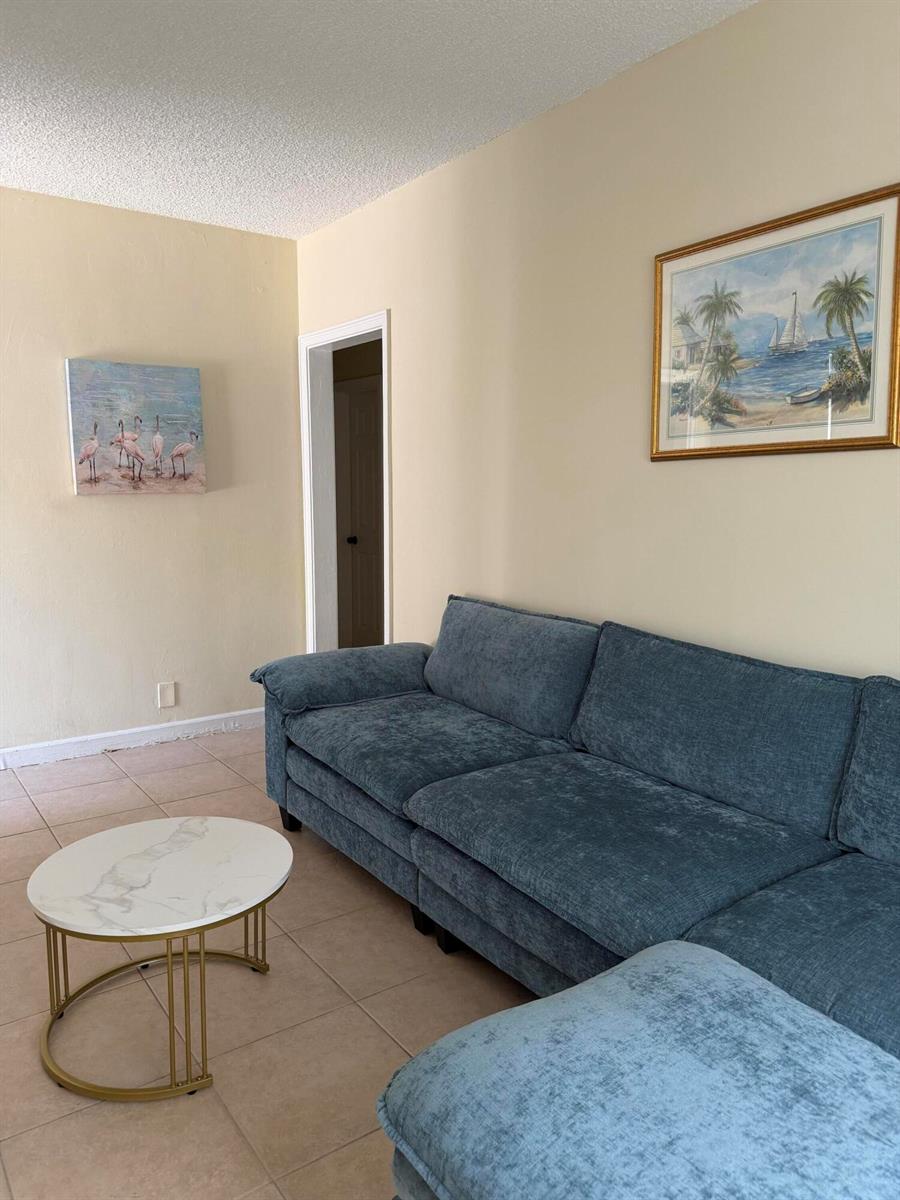 A living room features a blue sectional sofa, a marble-topped coffee table, and wall art — 224 Conniston Road # 2, West Palm Beach FL 33405, WEST PALM BEACH, FL