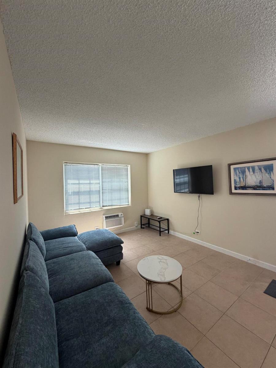 A living room features a blue sectional sofa, a marble coffee table, and a wall-mounted television — 224 Conniston Road # 2, West Palm Beach FL 33405, WEST PALM BEACH, FL