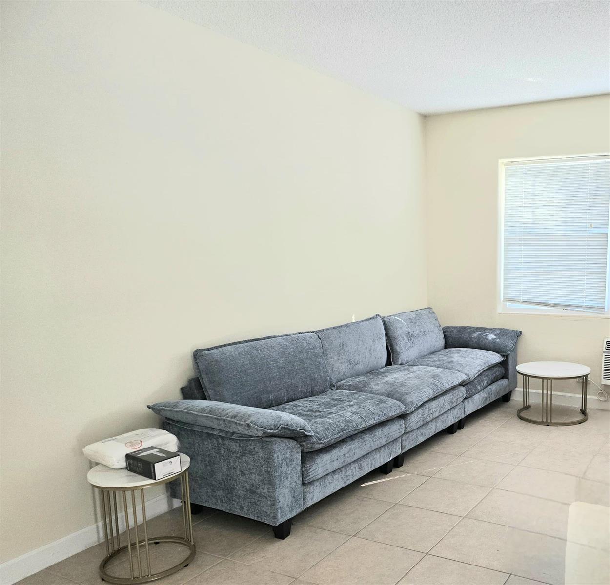 A living room features a large blue sofa, two small round side tables, and tile flooring — 224 Conniston Road # 2, West Palm Beach FL 33405, WEST PALM BEACH, FL