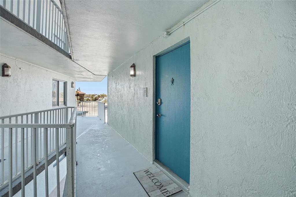 An exterior walkway leads to a blue front door with a welcome mat — 1571 S ATLANTIC AVENUE UNIT 2120, NEW SMYRNA BEACH, FL