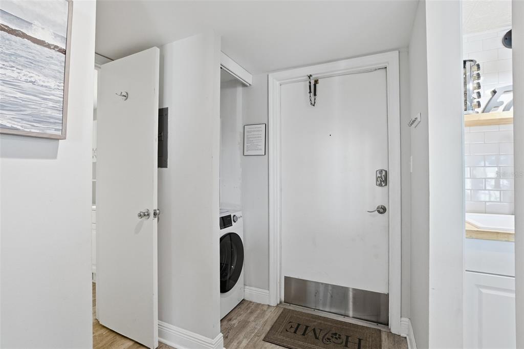 An entryway features a white door, a stacked washer and dryer, and wood-look flooring — 1571 S ATLANTIC AVENUE UNIT 2120, NEW SMYRNA BEACH, FL