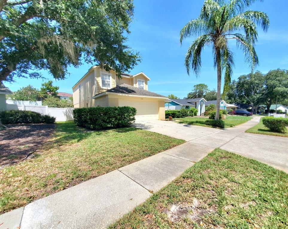 A two-story yellow house with a two-car garage and a palm tree in front — 2331 ROTHENFELD COURT, LAND O LAKES, FL