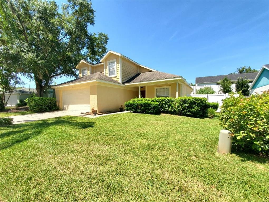 A two-story yellow house with a two-car garage and a large front lawn — 2331 ROTHENFELD COURT, LAND O LAKES, FL