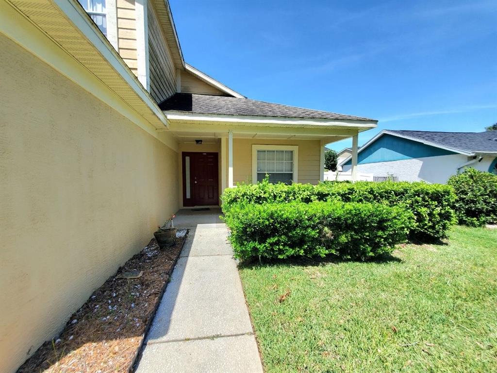 A concrete walkway leads to the front entrance of a house with beige stucco siding — 2331 ROTHENFELD COURT, LAND O LAKES, FL