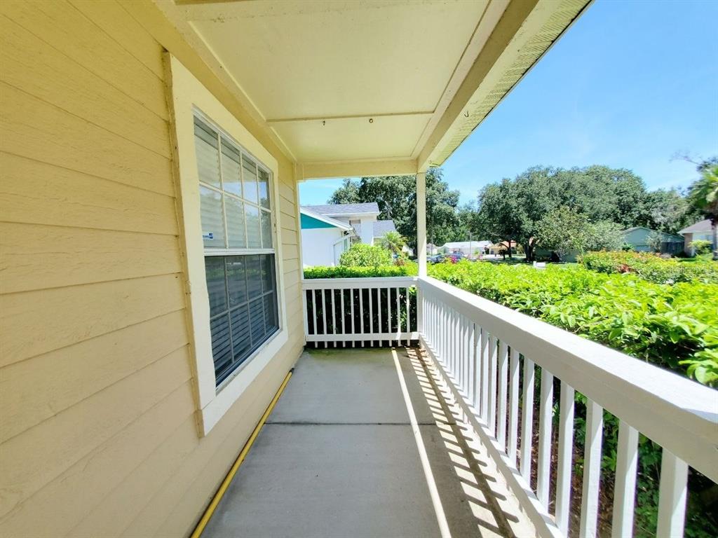 A covered porch with yellow siding, a white railing, and a concrete floor — 2331 ROTHENFELD COURT, LAND O LAKES, FL