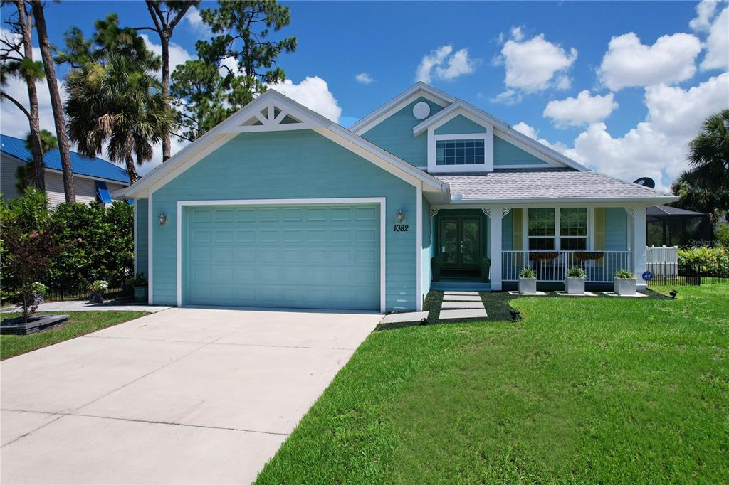 A light blue single-story house with a two-car garage and a front porch — 1082 MARCH DRIVE, PORT CHARLOTTE, FL