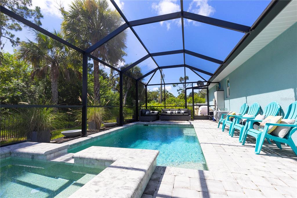 A screened-in patio features a swimming pool, a hot tub, and several turquoise outdoor chairs — 1082 MARCH DRIVE, PORT CHARLOTTE, FL
