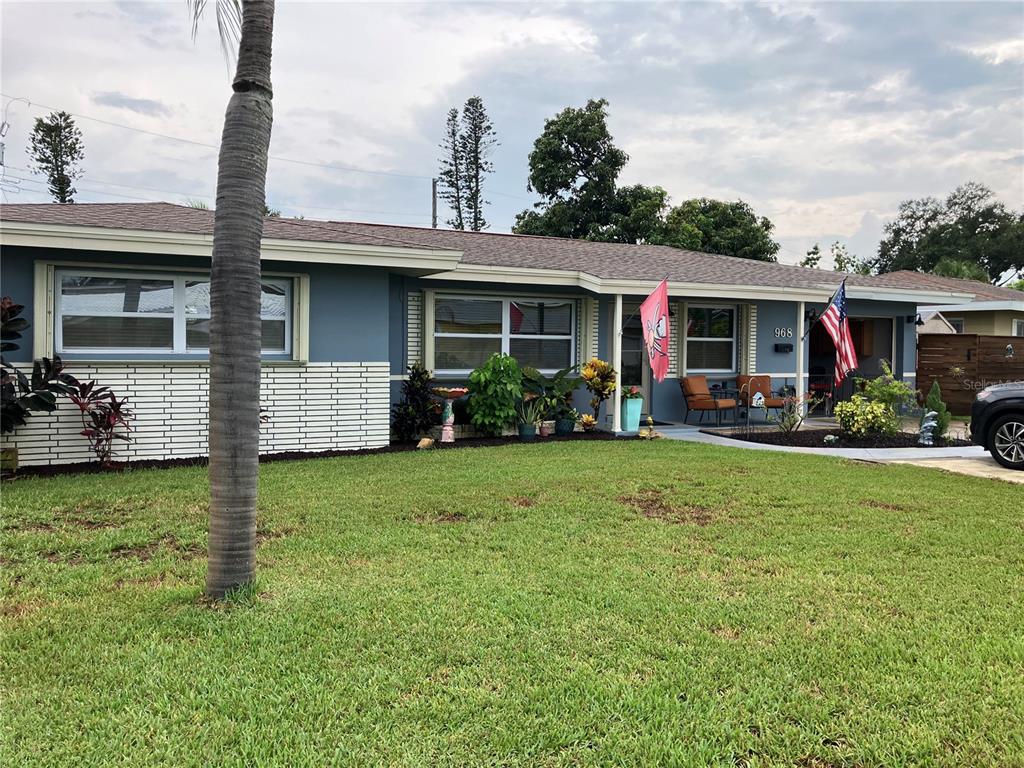 A single-story blue house with a white brick base, a front porch, and a lawn — 968 62ND PLACE S, ST PETERSBURG, FL