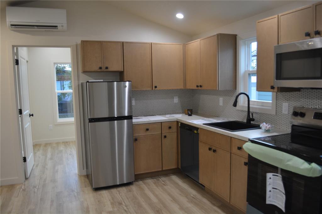 A kitchen features light wood cabinets, stainless steel appliances, a black sink, and tile backsplash — 630 THIRD STREET STREET, OVIEDO, FL
