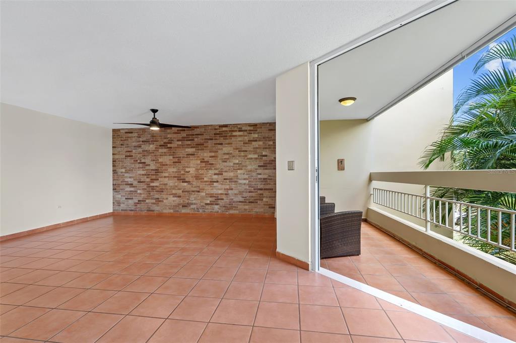 An indoor room with a brick accent wall and tile floors opens to a balcony — 30 Avenida JUAN CARLOS DE BORBÓN UNIT 2, GUAYNABO, PR