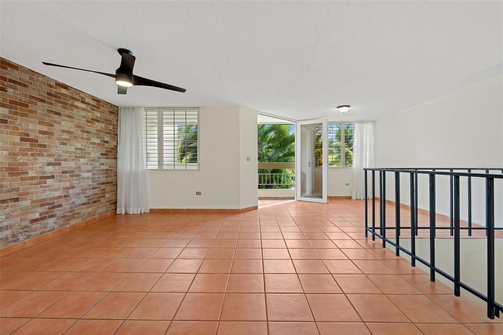 A bright living area features a brick accent wall, tile flooring, and a balcony entrance — 30 Avenida JUAN CARLOS DE BORBÓN UNIT 2, GUAYNABO, PR