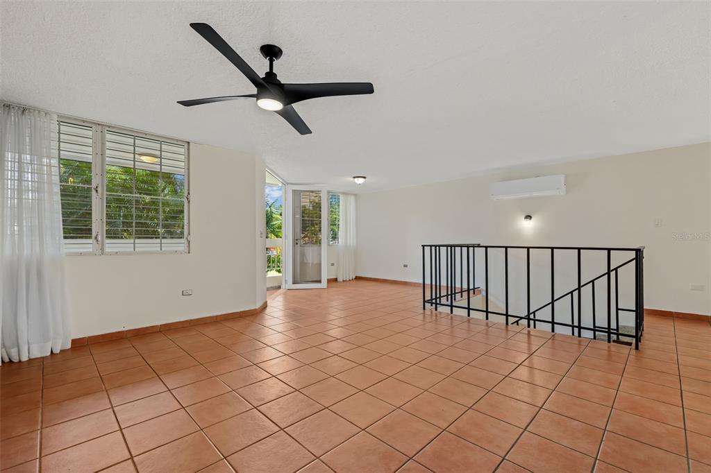 An open living area features terracotta tile flooring, a ceiling fan, and a staircase railing — 30 Avenida JUAN CARLOS DE BORBÓN UNIT 2, GUAYNABO, PR