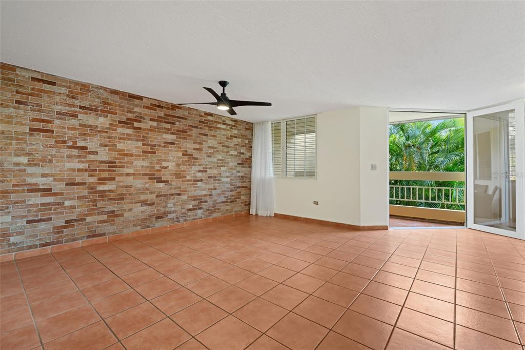An empty room with a brick accent wall, terracotta tile flooring, and a balcony entrance — 30 Avenida JUAN CARLOS DE BORBÓN UNIT 2, GUAYNABO, PR