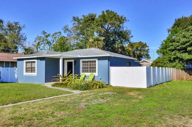 A blue single-story house with a white fence and two green chairs on the lawn — 816 E FRIERSON AVENUE, TAMPA, FL