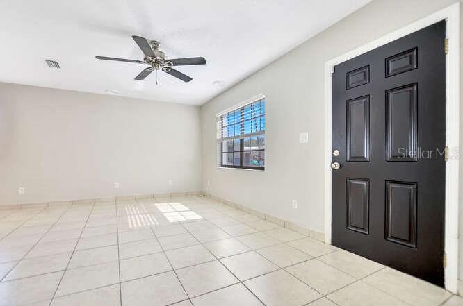 A room with light-colored tile flooring, a ceiling fan, a window, and a black door — 816 E FRIERSON AVENUE, TAMPA, FL