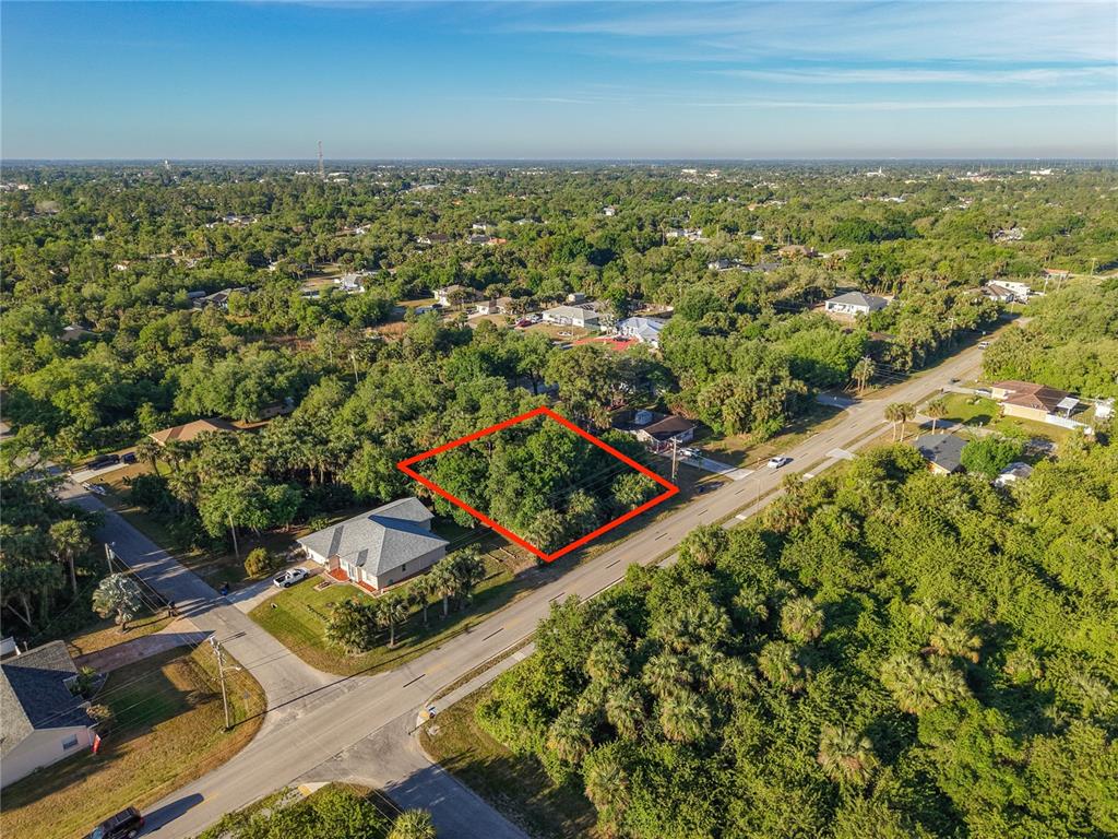 An aerial view shows a vacant, tree-covered lot outlined in red next to a house — 103 W 6TH STREET, LEHIGH ACRES, FL