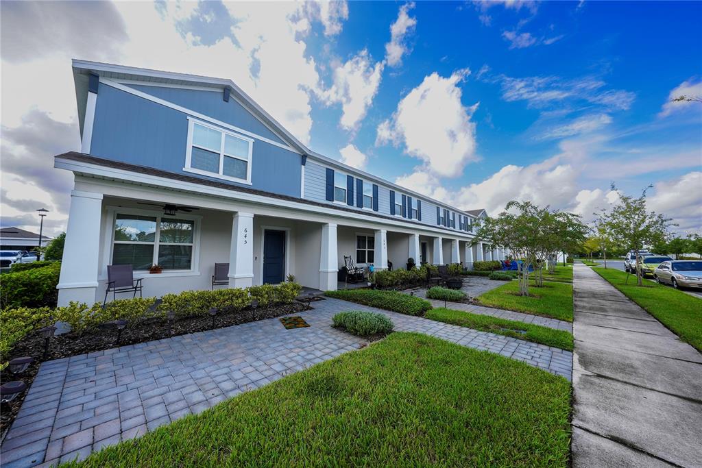 A blue and white multi-unit townhouse exterior features a covered front porch and paved walkway — 643 BELGROVE STREET, DEBARY, FL