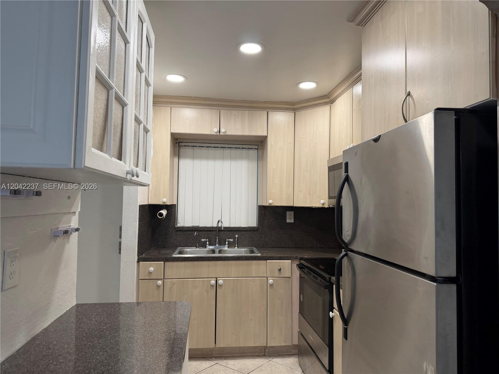 A kitchen features light wood cabinets, dark countertops, stainless steel appliances, and recessed lighting — NORTH MIAMI BEACH, FL