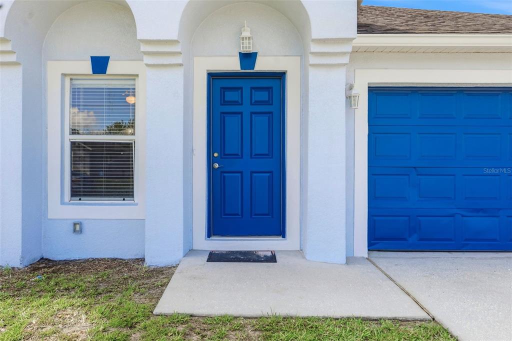 The exterior of a house features a blue front door and a blue garage door — 955 LOUVRE COURT, KISSIMMEE, FL