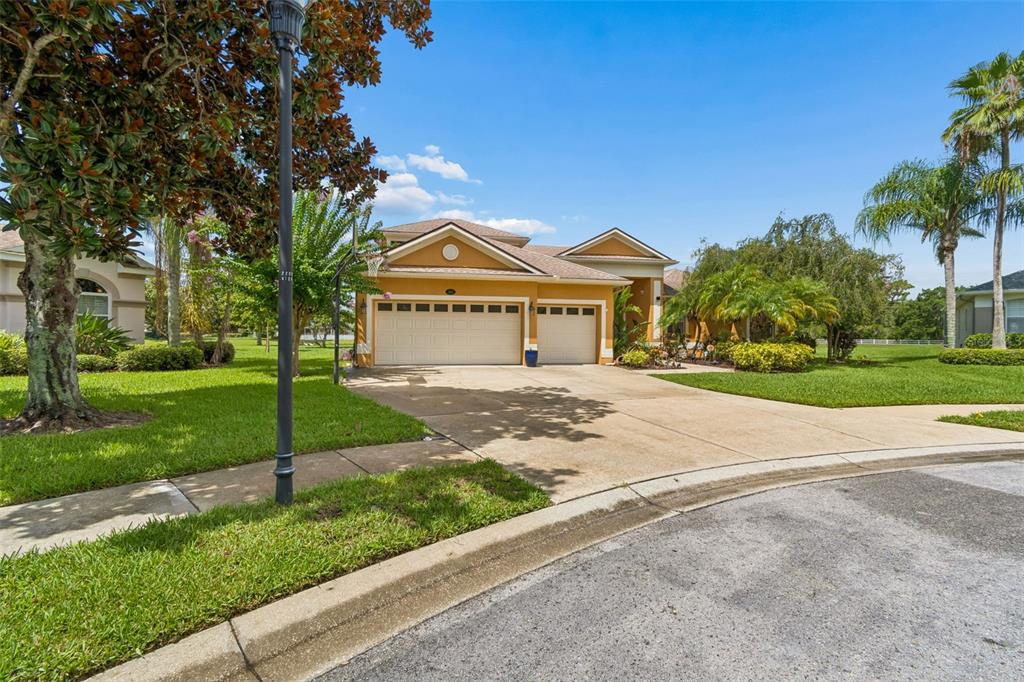 A single-story house with a three-car garage and a concrete driveway under a blue sky — 5303 CLOUDS PEAK DRIVE, LUTZ, FL