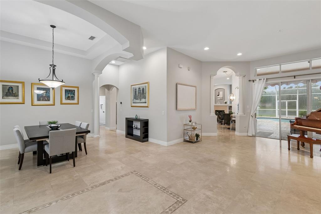 A spacious dining and living area features tile floors, arched doorways, and a grand piano — 5303 CLOUDS PEAK DRIVE, LUTZ, FL