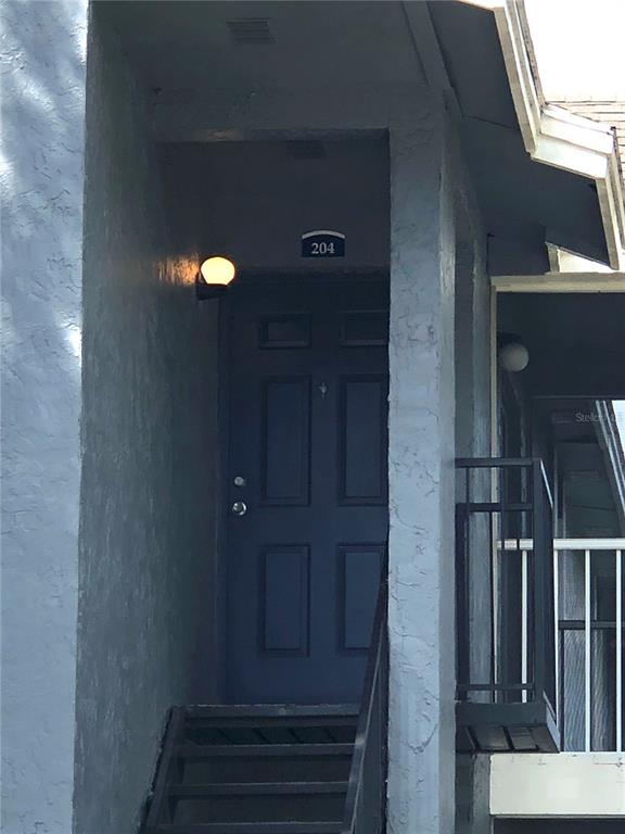 An exterior view of a dark blue apartment door labeled 204 at the top of stairs — 3831 BOWLINE CIRCLE UNIT 204, KISSIMMEE, FL