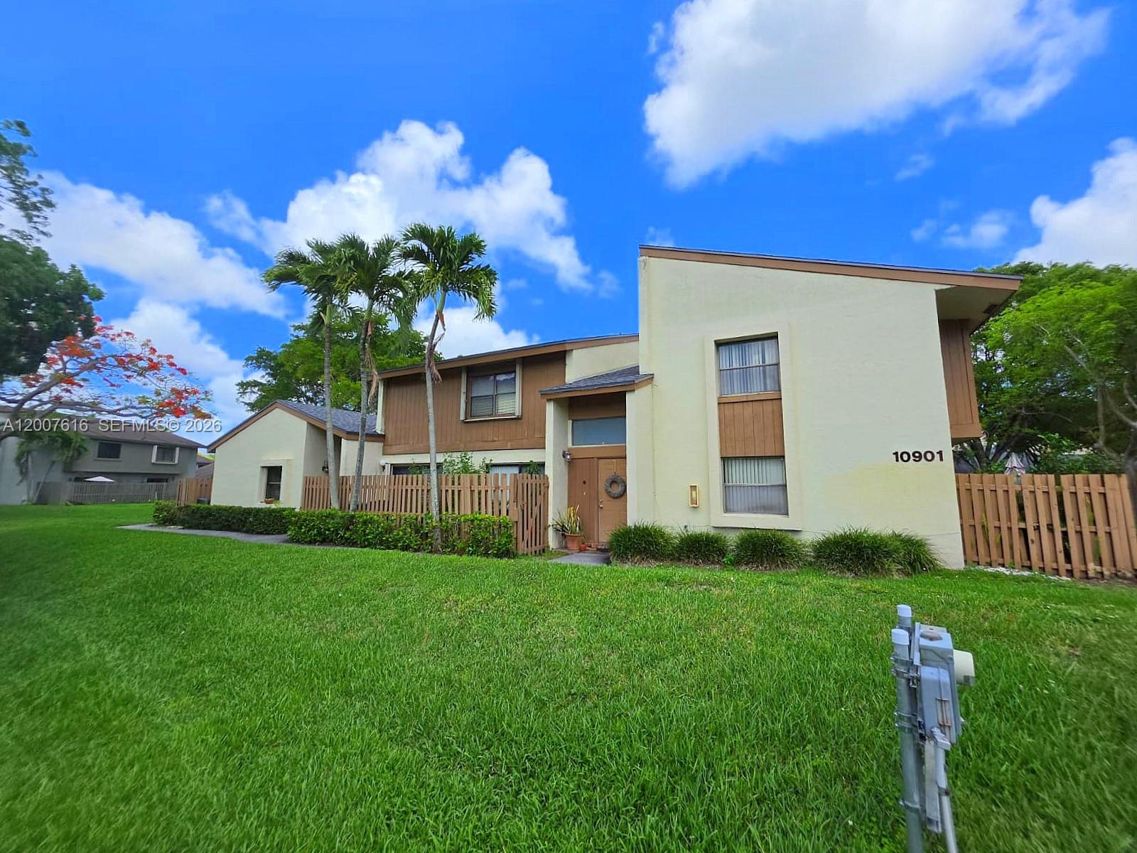 A two-story house with light-colored stucco walls, brown wood accents, and palm trees in front — 10901 SW 113th Pl # 66B, Miami FL 33176, MIAMI, FL