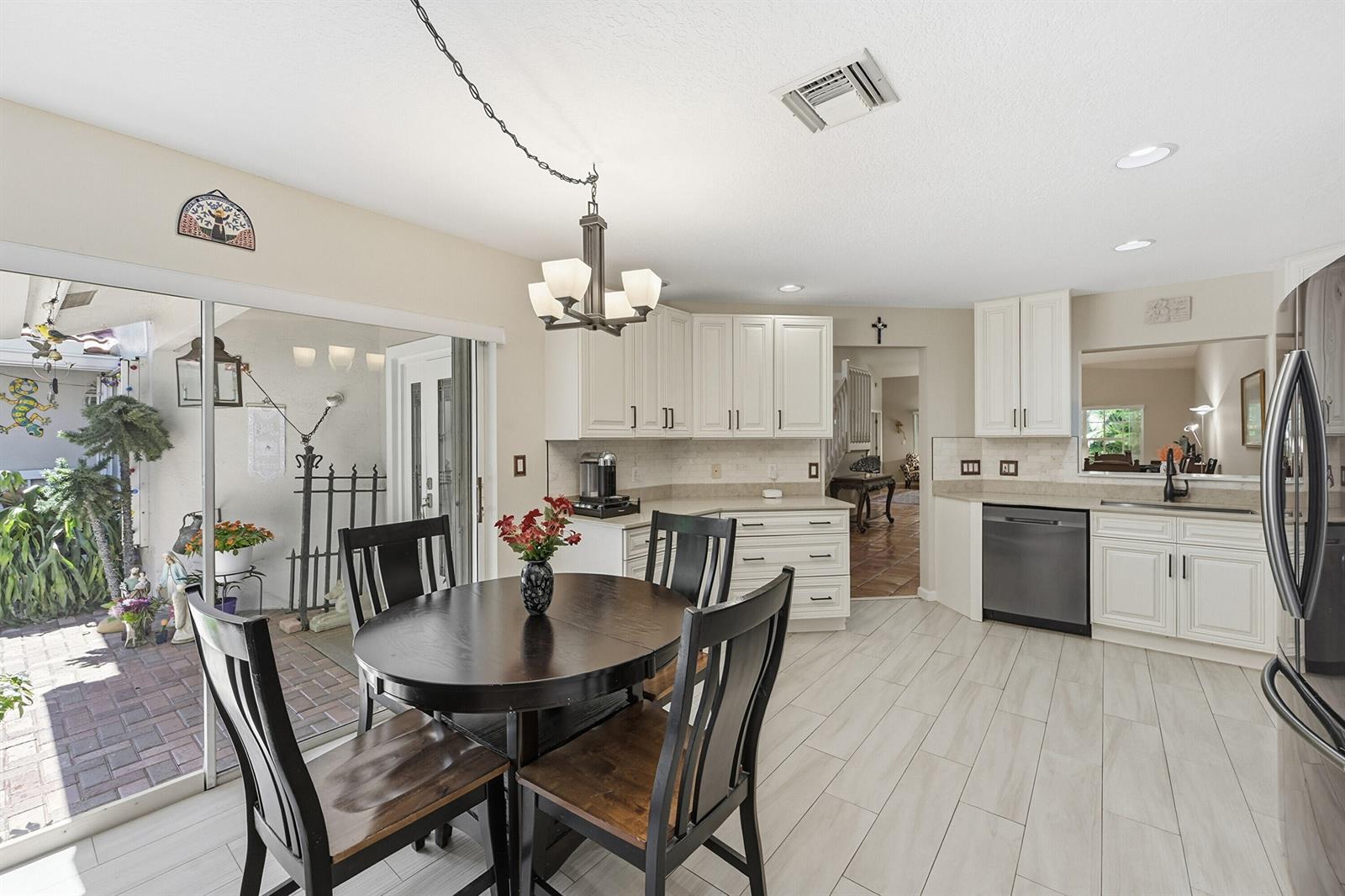 A kitchen with white cabinets, stainless steel appliances, and a dining table near sliding doors — 4115 Carriage Drive # P2, Pompano Beach FL 33069, POMPANO BEACH, FL