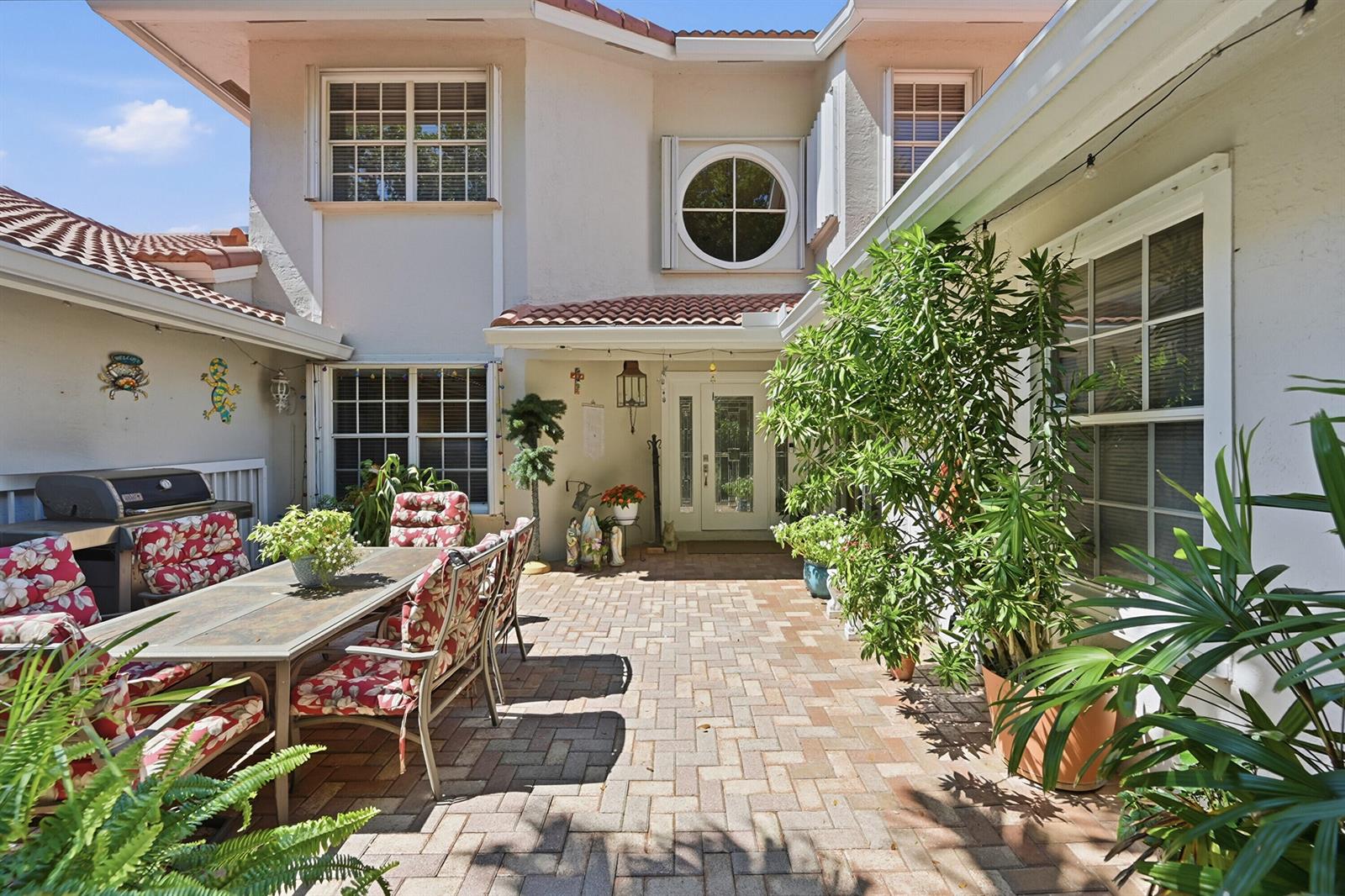 A paved courtyard features a dining set, potted plants, and a grill near the house entrance — 4115 Carriage Drive # P2, Pompano Beach FL 33069, POMPANO BEACH, FL