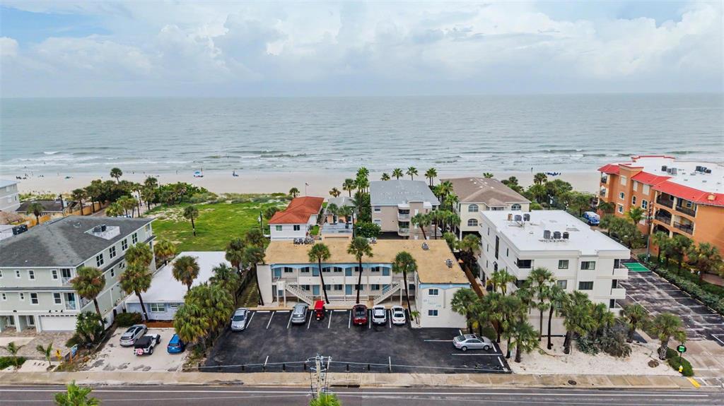 An aerial view shows a multi-story apartment building with a parking lot near the beach — 2110 GULF BOULEVARD UNIT 9, INDIAN ROCKS BEACH, FL