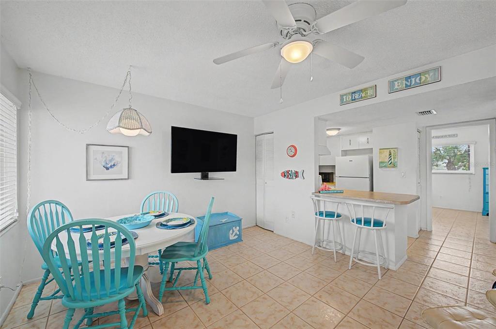 A dining area with a white table, turquoise chairs, and a breakfast bar with stools — 2110 GULF BOULEVARD UNIT 9, INDIAN ROCKS BEACH, FL