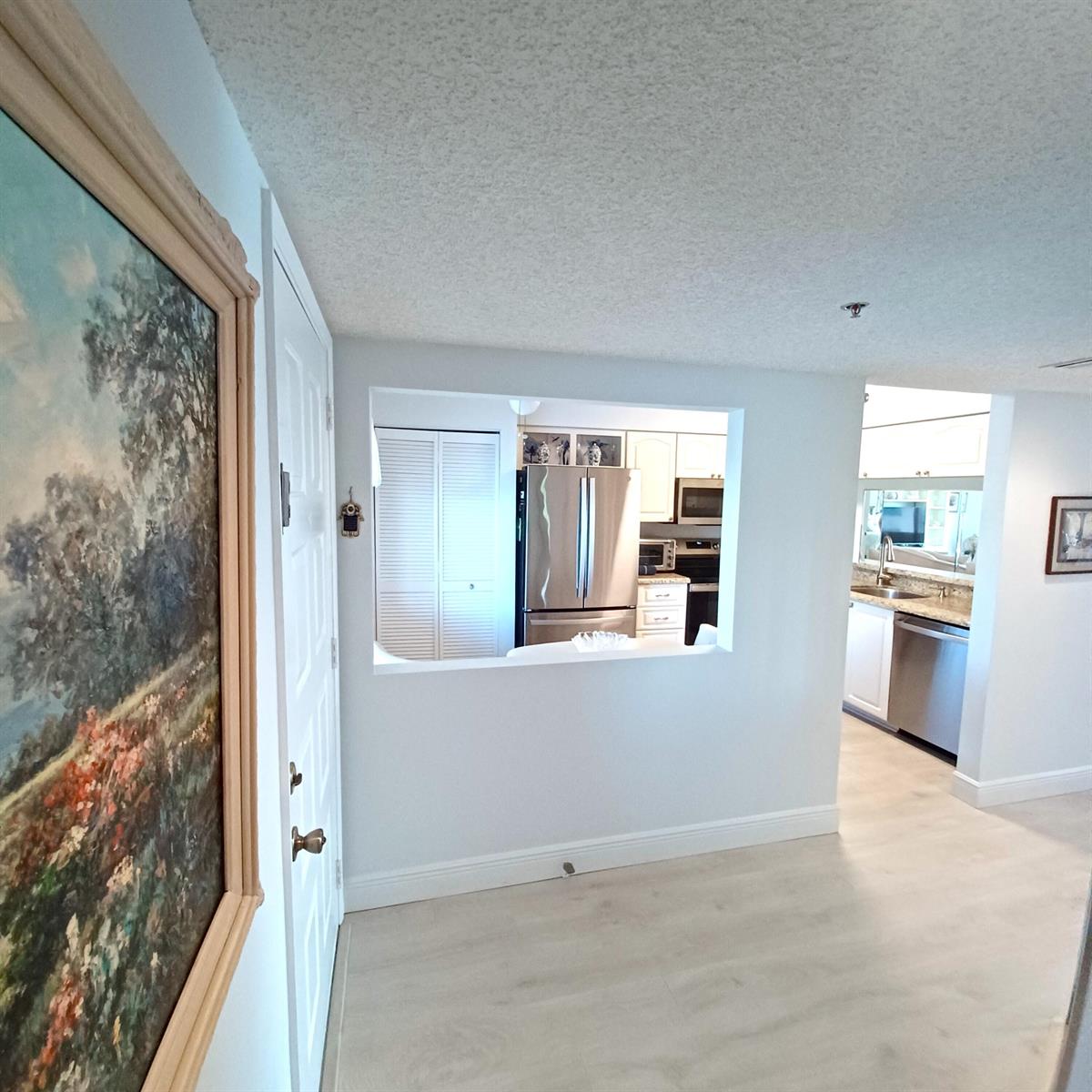 A view of an entryway leading into a kitchen with stainless steel appliances and cabinetry — 7260 Kinghurst Drive # 406, Delray Beach FL 33446, DELRAY BEACH, FL