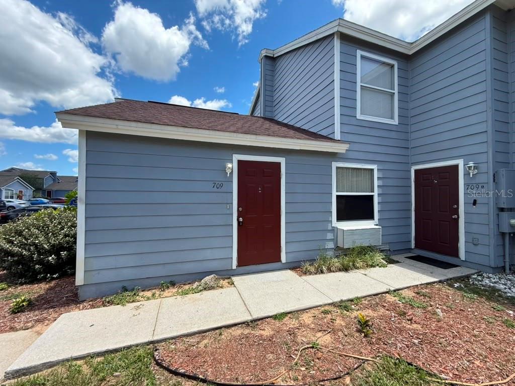 The exterior of a two-story blue house features two red doors and a concrete walkway — 709 ORCHID DRIVE UNIT B, DAVENPORT, FL