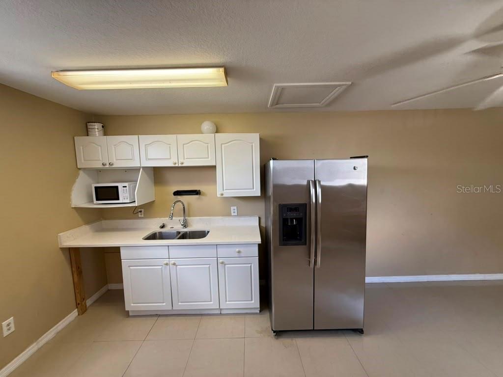 A kitchen features white cabinets, a stainless steel refrigerator, a sink, and a microwave — 709 ORCHID DRIVE UNIT B, DAVENPORT, FL