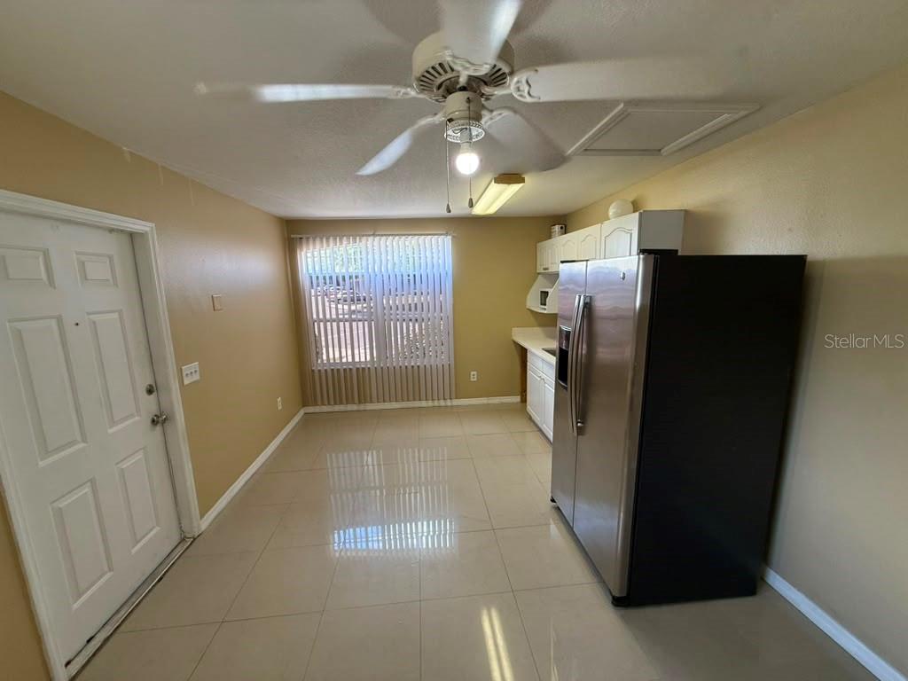A kitchen features tile flooring, a stainless steel refrigerator, white cabinets, and a ceiling fan — 709 ORCHID DRIVE UNIT B, DAVENPORT, FL