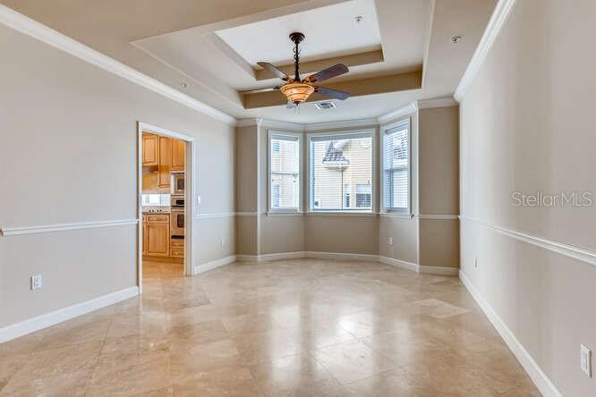 A dining room with tile floors, a tray ceiling, and a view into the kitchen — 8749 THE ESPLANADE UNIT 32, ORLANDO, FL