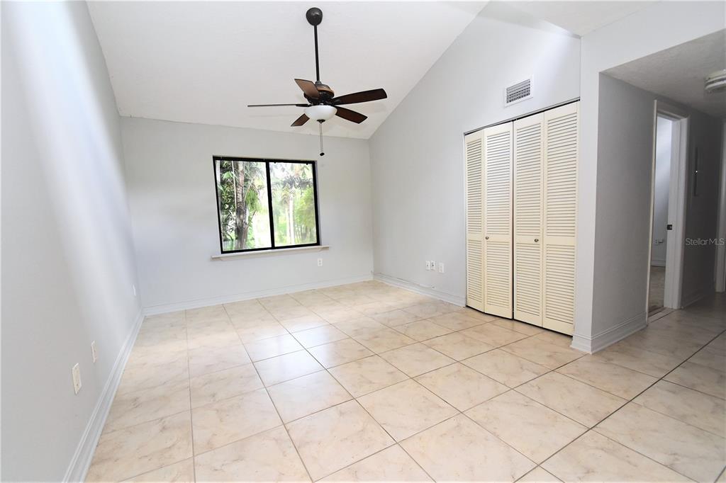 An open living area features light-colored tile flooring, white walls, and sliding glass balcony doors — 1601 PELICAN POINT DRIVE UNIT HA215, SARASOTA, FL