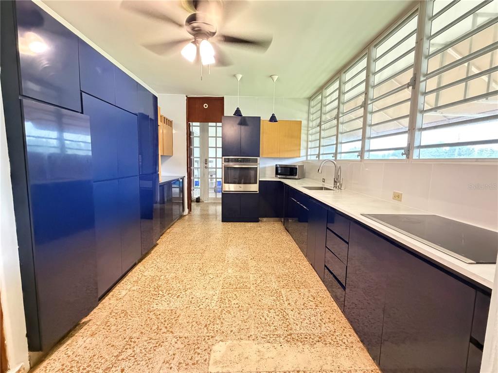 A kitchen features blue cabinetry, a built-in oven, a sink, and speckled tile flooring — Lot 119 VILLA SONSIRE, MAYAGUEZ, PR