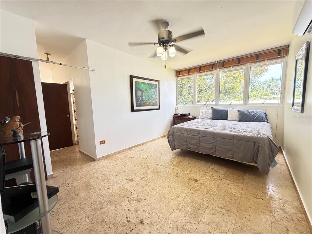 A bedroom features a bed, a ceiling fan, and light-colored tile flooring — Lot 119 VILLA SONSIRE, MAYAGUEZ, PR