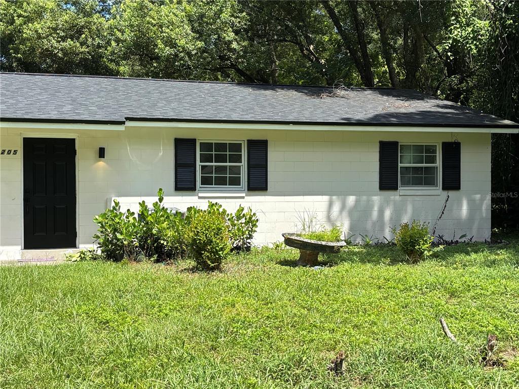 A white, single-story concrete block house with a black door and dark shutters — 205 S CHANDLER AVENUE, DELAND, FL