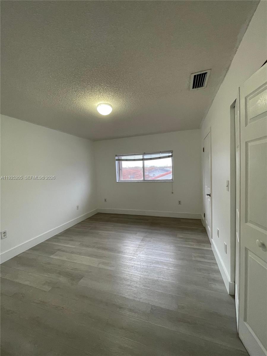 An empty bedroom features light-colored wood-look flooring, white walls, and a single window — 3375 W 76th St # 211, Hialeah FL 33018, HIALEAH, FL