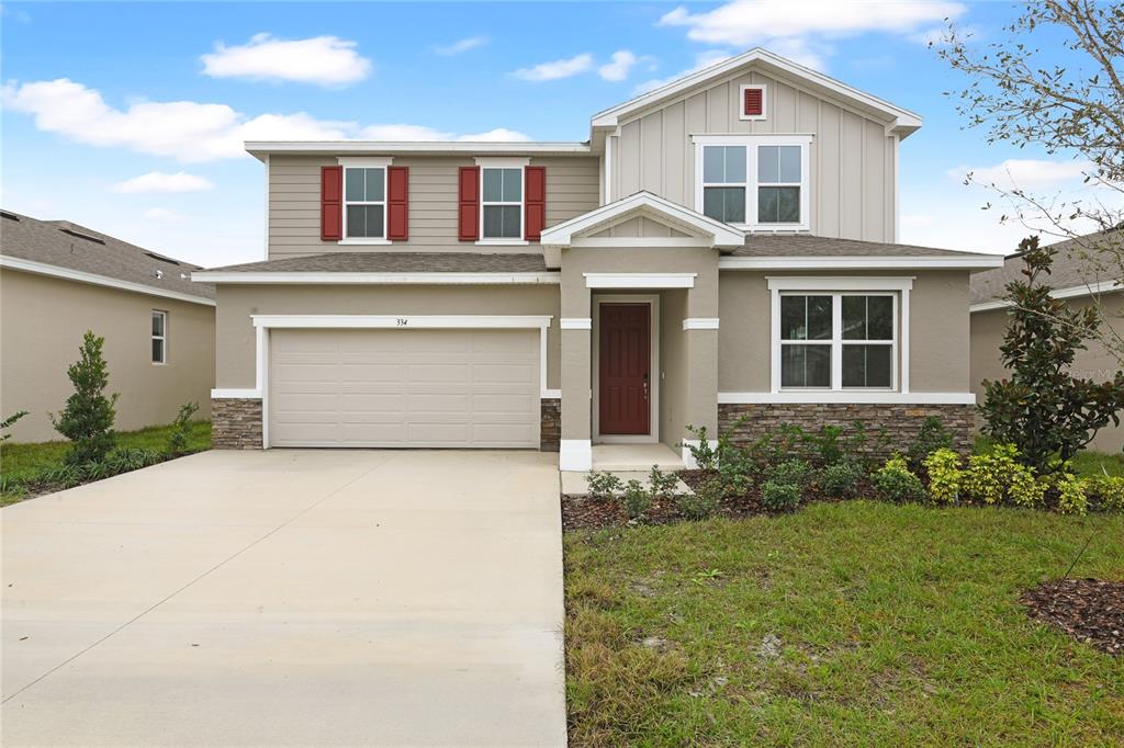 A two-story suburban house with a beige exterior, red shutters, and a two-car garage — 334 ALEXANDRITE STREET, DELAND, FL