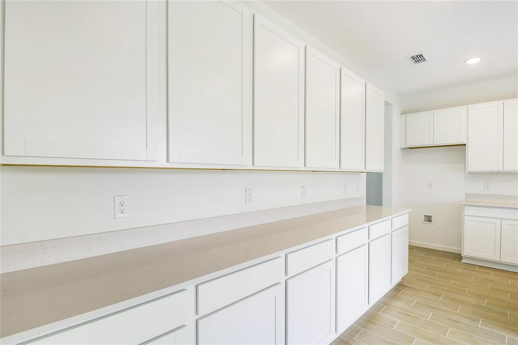 A kitchen features white shaker cabinets, light countertops, and wood-look tile flooring — 334 ALEXANDRITE STREET, DELAND, FL