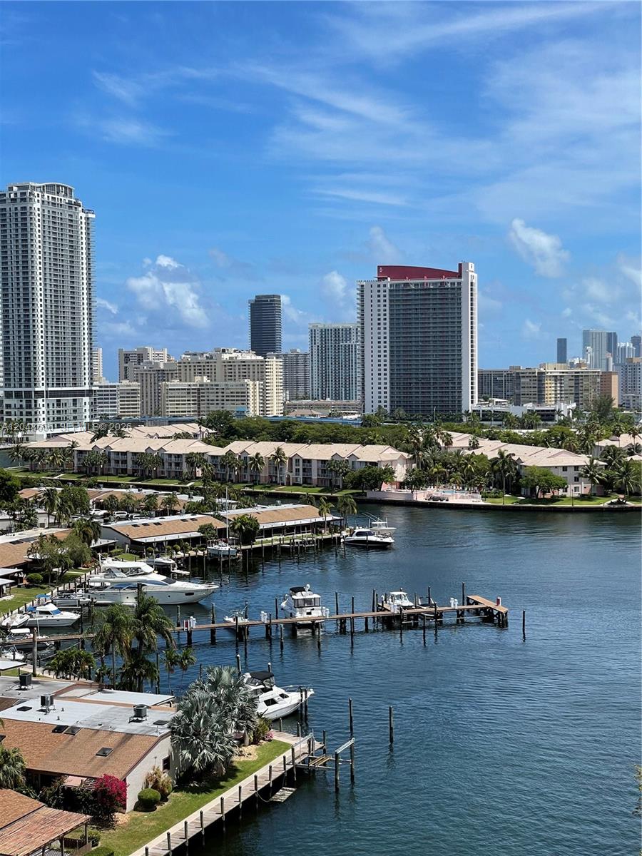 An elevated view of a canal with docked boats, low-rise residential buildings, and distant skyscrapers — 2500 PARKVIEW DR # 1405, Hallandale Beach FL 33009, HALLANDALE BEACH, FL