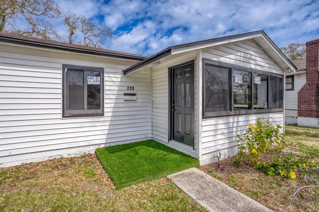 The exterior of a white house features a black front door and dark-framed windows — 711 19TH AVENUE S, ST PETERSBURG, FL