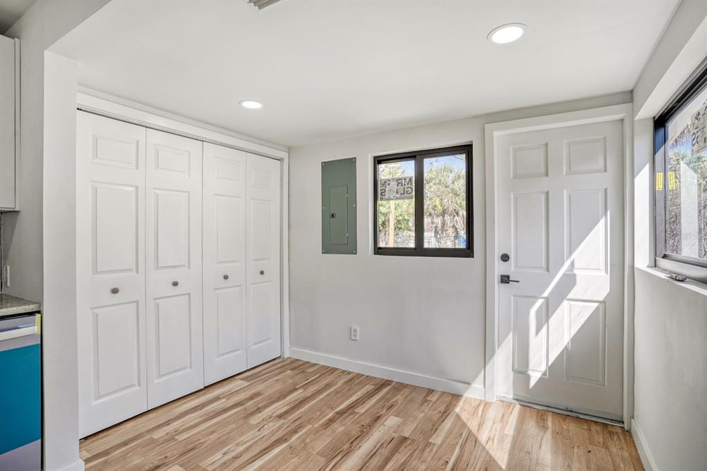 A room with wood-look flooring, white bi-fold closet doors, a window, and an exterior door — 711 19TH AVENUE S, ST PETERSBURG, FL
