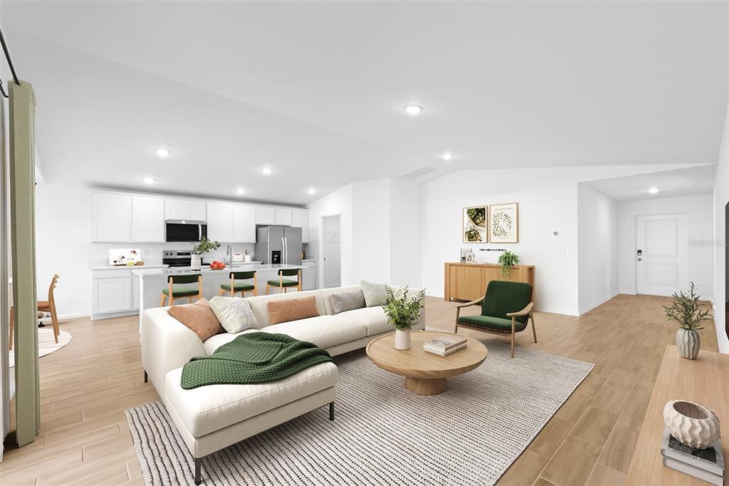 A bright, open-concept living room and kitchen featuring white cabinetry, light wood floors, and furniture — 15122 CANNELL LANE, PORT CHARLOTTE, FL